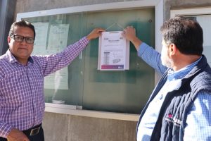 Dos personas de pie sosteniendo lista de ubicación de casillas