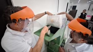 Dos personas vertiendo credenciales en una trituradora