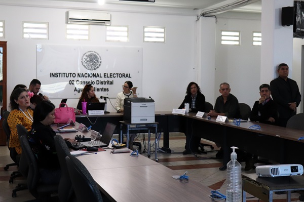 ocho personas sentadas en sala de sesiones de consejo distrital