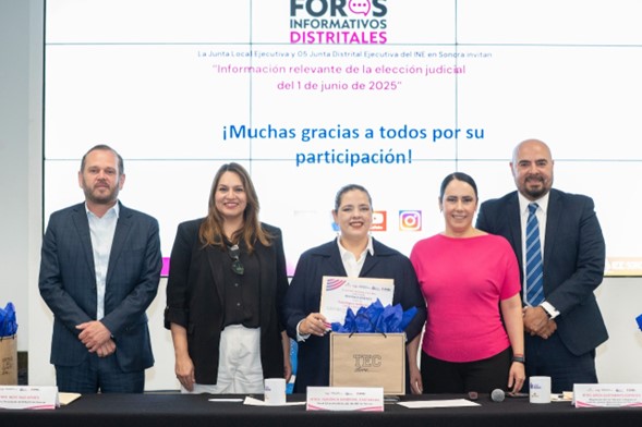 cinco personas de pie entregándole un reconocimiento a una ponente en el foro