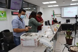 tres personas sosteniendo credenciales para votar
