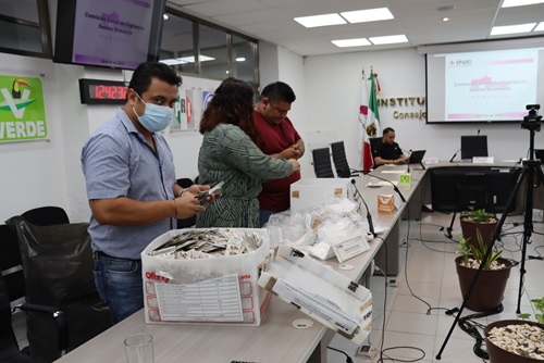 tres personas sosteniendo credenciales para votar