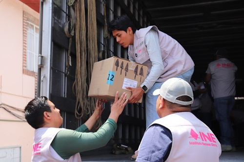 Tres personas bajando cajas de un camión
