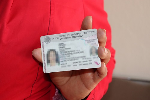 la mano de una persona sosteniendo una credencial para votar