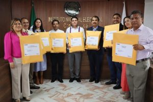 personal del INE en Oaxaca mostrando sobres amarillos