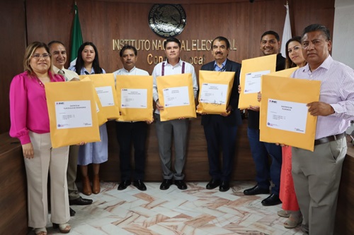 personal del INE en Oaxaca mostrando sobres amarillos