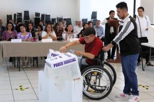 hombre en silla de ruedas introduciendo boletas en urna