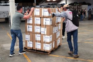 Dos funcionarios del INE en Chihuahua empujando un carrito con cajas apiladas