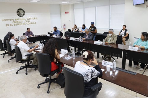 varias personas sentadas alrededor de una mesa ovalada en las instalaciones del INE en Coahuila