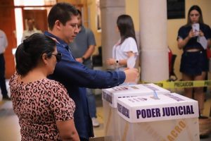 personas introduciendo boleta electoral en Urna