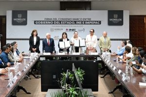 personas de pie mostrando un convenio firmado