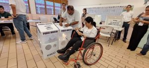 Mujer en silla de ruedas introduciendo boletas en urna del INE en Quintana Roo
