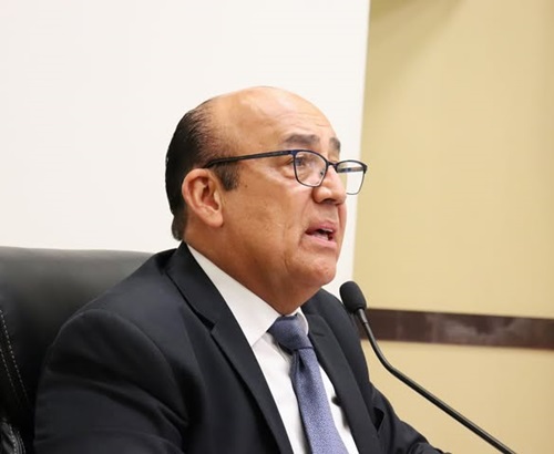 Hombre tez morena de lentes y calvo, hablando frente a un micrófono