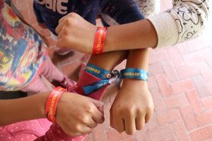 manos de niñas, niños y adolescentes mostrando pulseras de la Consulta Infantil