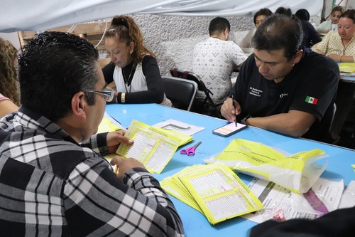 dos personas sentadas realizando cómputos distritales