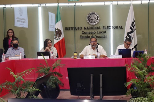 cuatro personas de consejo local sentados en salón de sesiones