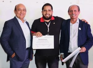 tres personas de pie, dos de ellas sosteniendo su reconocimiento