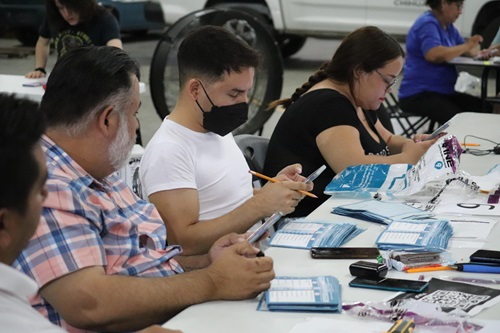 cinco personas sentadas en una mesa realizando cómputos distritales