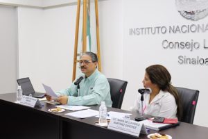 Dos personas sentadas en una mesa, una de ellas leyendo un documento