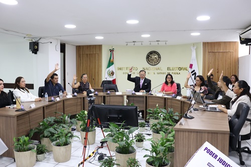 integrantes de consejo local sentados y votando a mano alzada