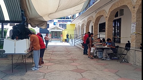 varias personas de pie emitiendo su voto en una casilla