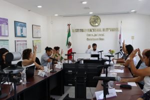 integrantes de consejo local sentados en salón de sesiones votando a mano alzada