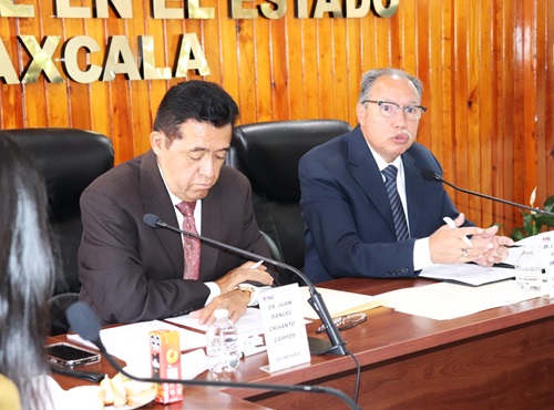 dos personas sentadas en una mesa dialogando