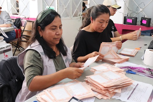 dos trabajadoras del INE con boletas electorales en las manos
