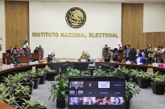 Salón de sesiones y pantalla con recuadros de la participación de las personas Consejeras Electorales.