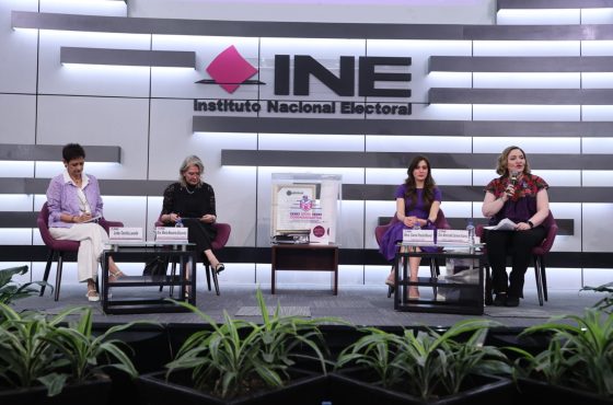 Imagen abierta en el auditorio del instituto con las personas participantes en el conversatorio 1 sentados en el estrado al frente del recinto y letrero del Instituto Nacional Electoral.