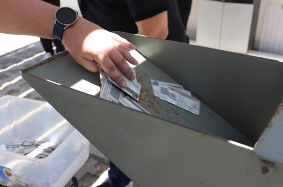 Aparece una mano vertiendo credenciales para votar a una trituradora