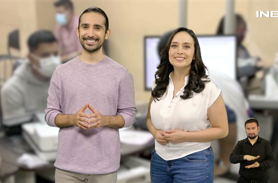 Mujer y hombre de pie sonriendo al frente con un módulo de atención ciudadana al fondo