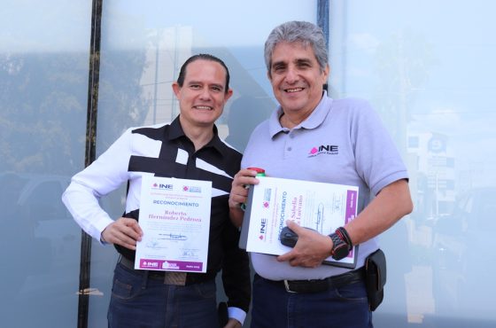 Dos trabajadores del INE mostrando el reconocimiento que le dieron por su buen desempeño