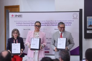 Participantes de la Firma de pie con el documento en las manos.