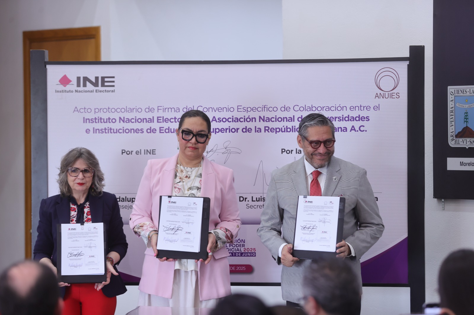 Participantes de la Firma de pie con el documento en las manos.