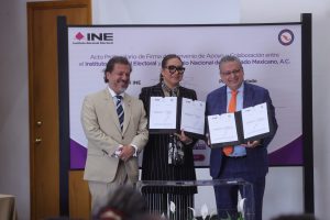 Participantes de la Firma de pie con el documento en las manos.