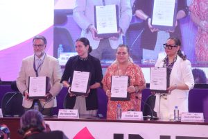 Participantes de la Firma de pie con el documento en las manos.