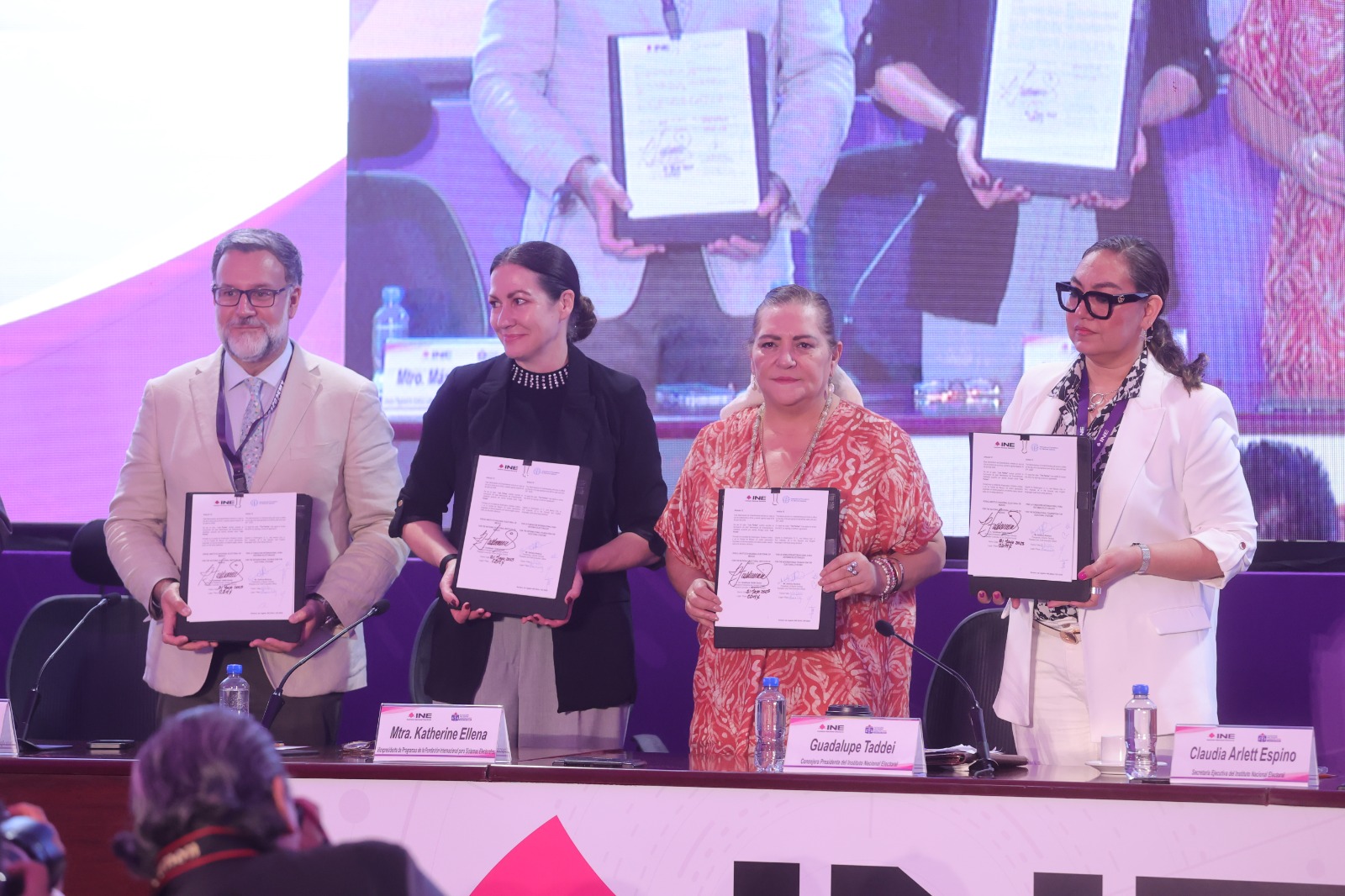 Participantes de la Firma de pie con el documento en las manos.