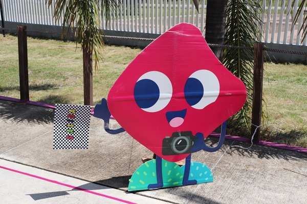 muñequito de boleta con ojitos, una cámara fotográfica y una bandera de señalización