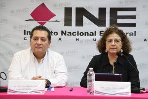 una mujer y un hombre sentados frente a una mesa con mantel rosa