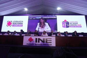 Participantes de la conferencia sentados en el estrado de la Macrosala de prensa