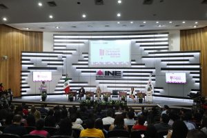 Personas participantes y público asistente al evento, sentados en el auditorio del instituto.