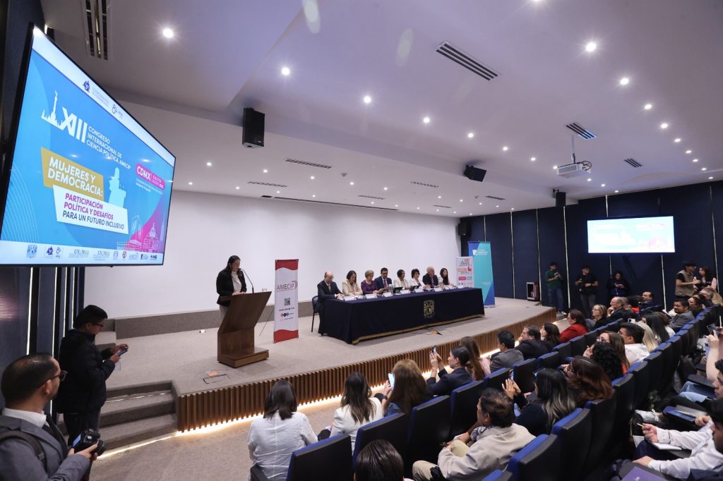 Personas participantes y público asistente al evento, sentados en el auditorio.