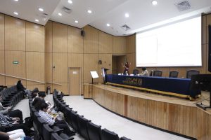 Personas participantes y público asistente al evento, sentados en el auditorio.