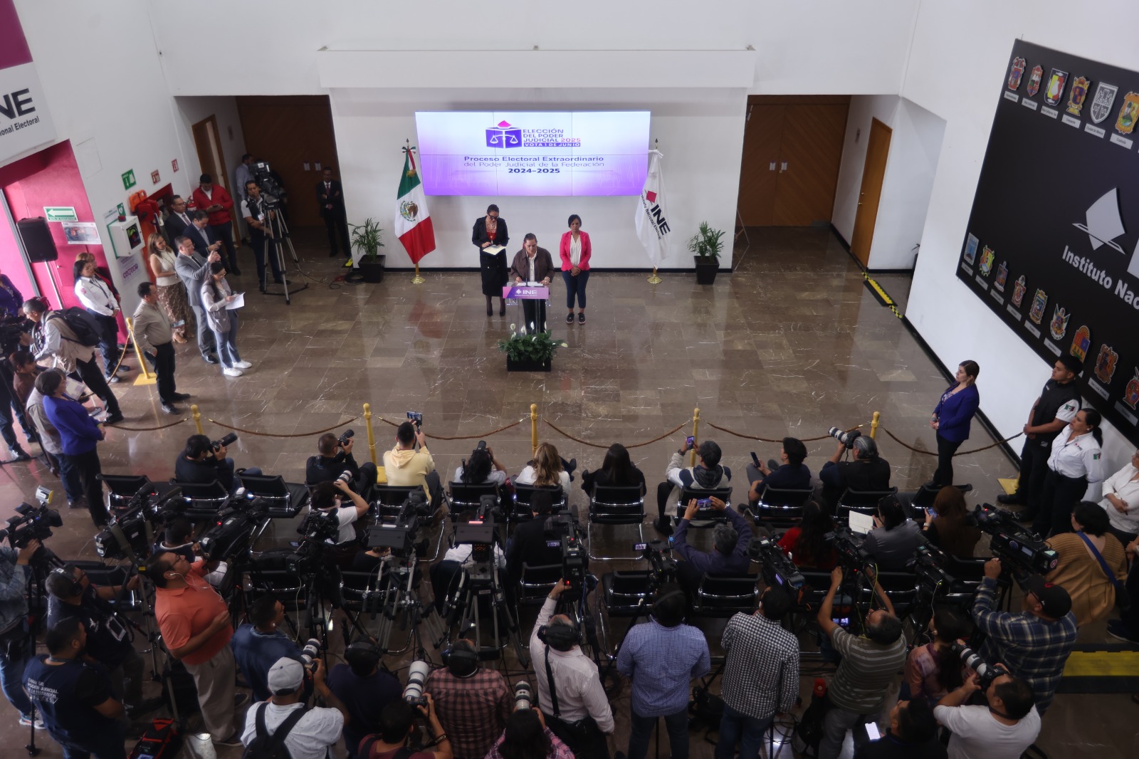Imagen abierta en el lobby del instituto con las personas participantes sentados en el estrado al frente de la audiencia.