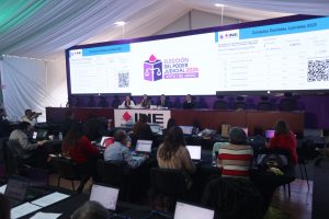 Participantes de la conferencia sentados en el estrado de la Macrosala de prensa.