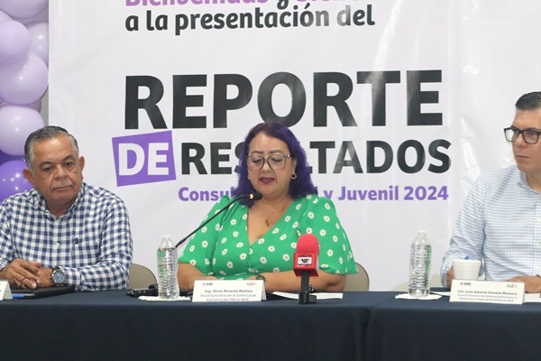 mujer vestido verde con lunares blancos sentada frente a un micrófono