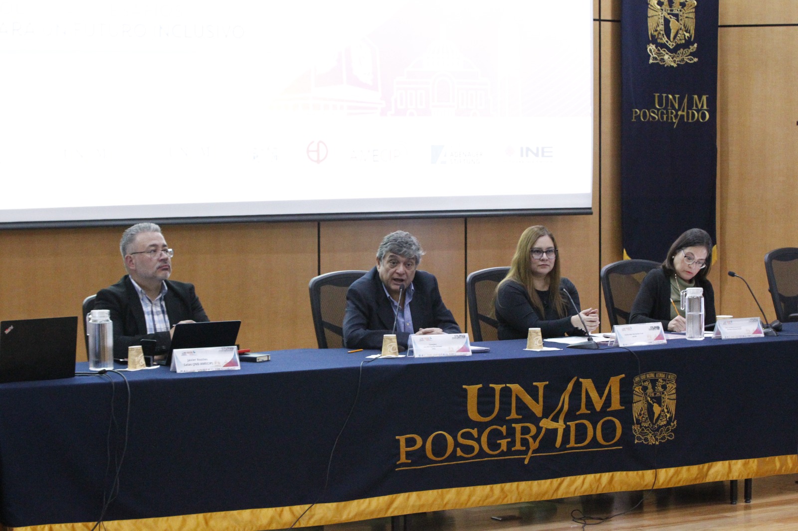 Personas participantes del evento, sentados en el estrado.
