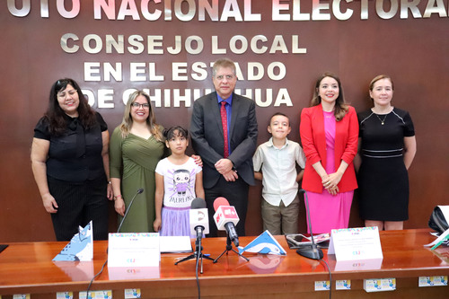 personas adultas y dos niños de pie frente a una letras doradas