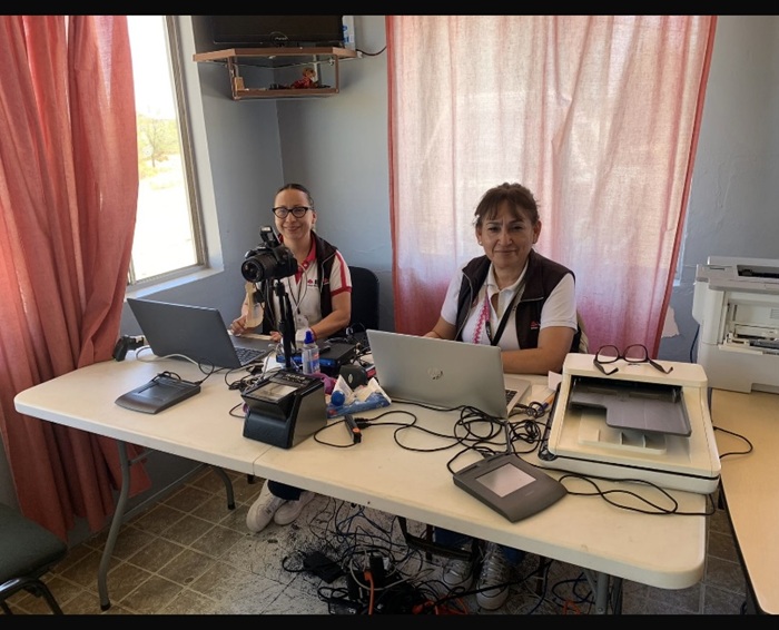 Dos personas sentadas frente a una mesa con computadoras